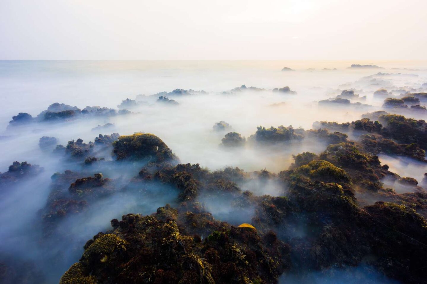 Waves crashing over rocks before sunset