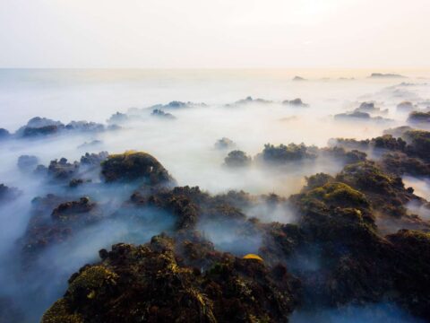 Waves crashing over rocks before sunset