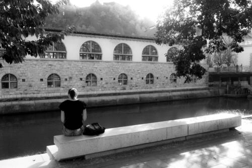 a woman sitting along the river and thinking 