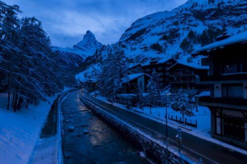 a mountain and canal with snow at dusk